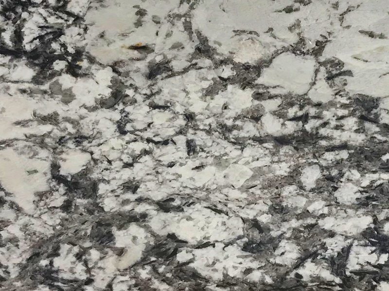 Superficie de granito blanco perla con vetas grises y patrón natural elegante.